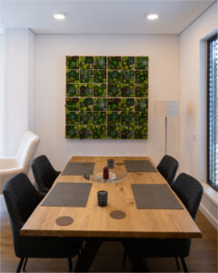 Essbereich im 2B Mikrohaus mit Holztisch, vier Stühlen und einer großen Mooswand als Highlight.