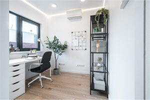 Helles Arbeitszimmer im 2B Mikrohaus mit großem Fenster, Schreibtisch und offenem Regal.