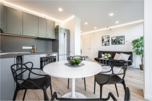 Offene Küche und Wohnbereich im 2B Mikrohaus mit rundem Esstisch, modernen Stühlen und Deko.