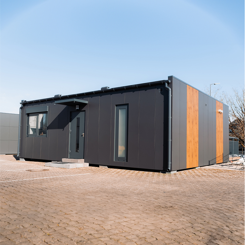 Außenansicht eines 2B Mikrohaus mit moderner Fassade in Grau und Holzoptik.